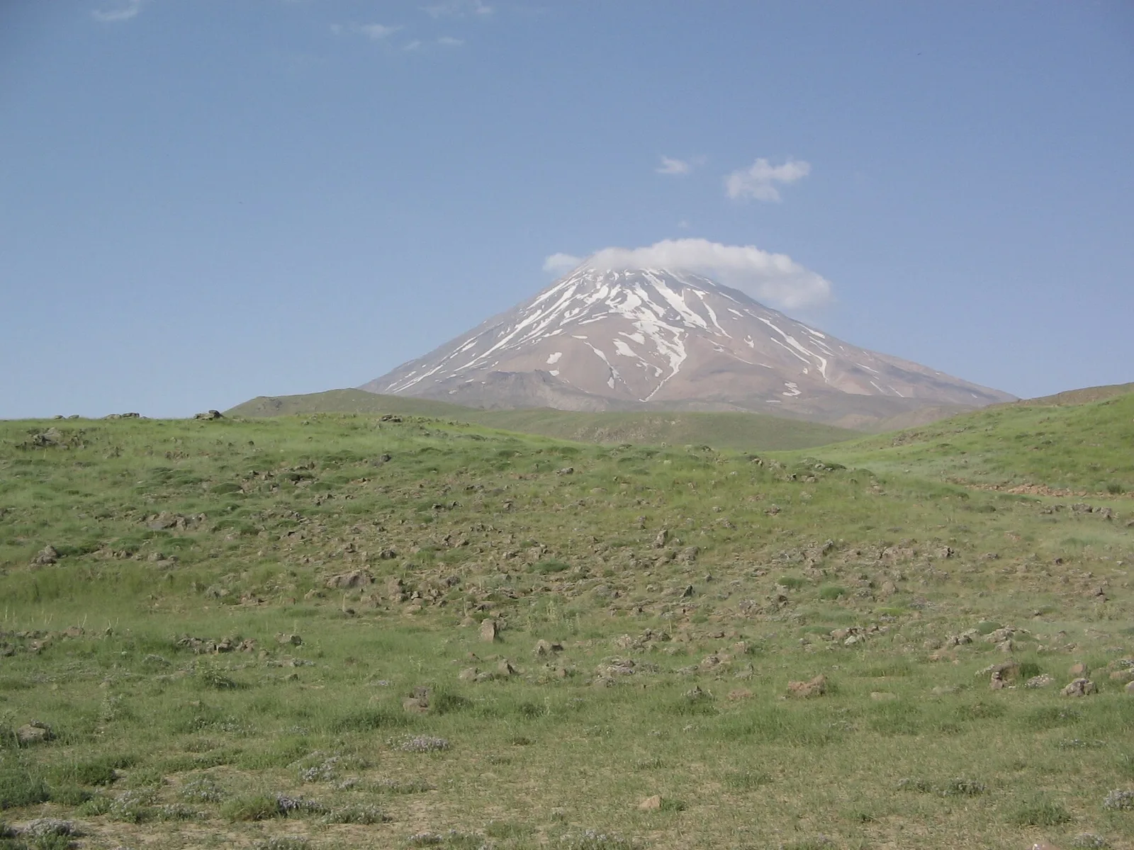 Snow-capped Mount Damavand rising above green foothills